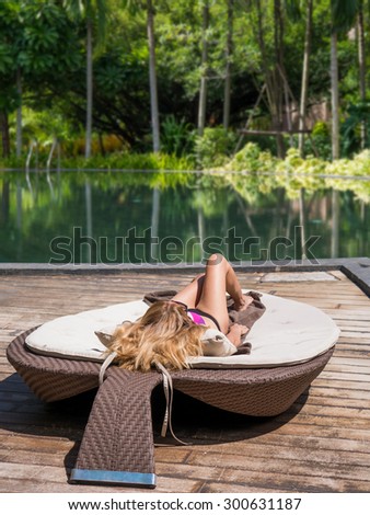 Young beautiful girl resting by the swimming pool