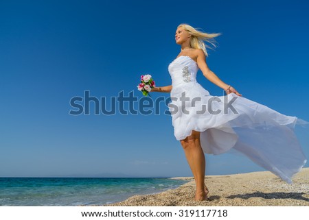 Young bride in wedding drees having fun on the beach in Greece