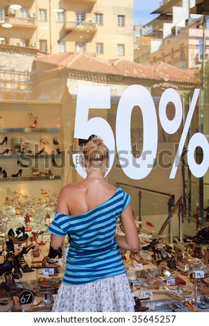 Woman in front of a shop Window With Sale Banners. Shopping Series.