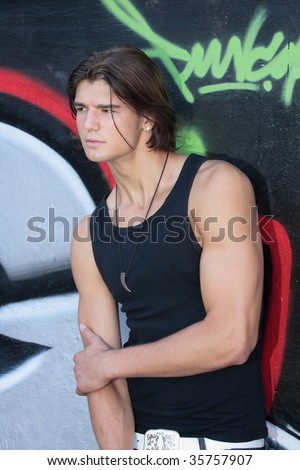 young handsome man in front of graffiti wall