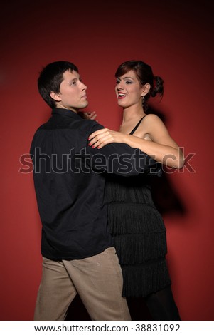 A beautiful young couple dancing salsa over red background