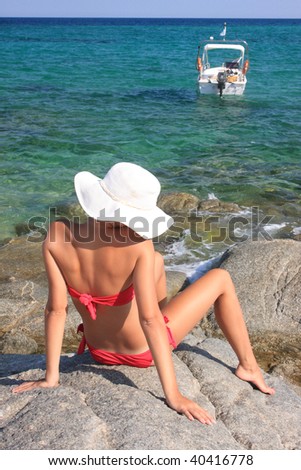 Young beautiful tanned woman in bikini resting by the sea in Greece