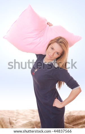 A beautiful young Woman having pillow fight in bed