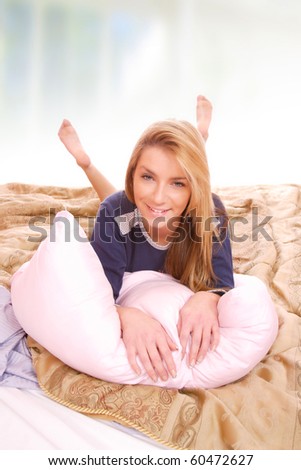 Young happy smiling woman on bed at morning