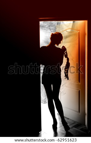 Outlines of a beautiful young woman standing by a door
