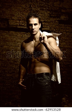 Fashion shot of a young handsome man in casual glamour clothes near the brick wall.