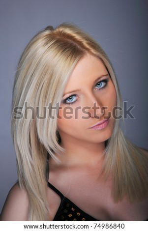 Young woman with beautiful blond hair, posing over gray background
