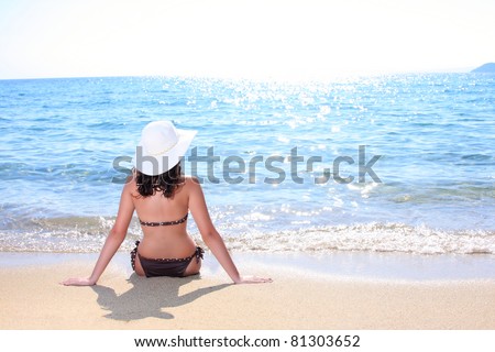 A beautiful woman facing the sea on a vacant beach in paradise