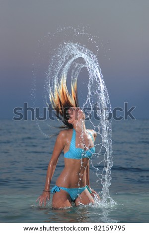 cute girl on the beach in Greece splashing out of the water