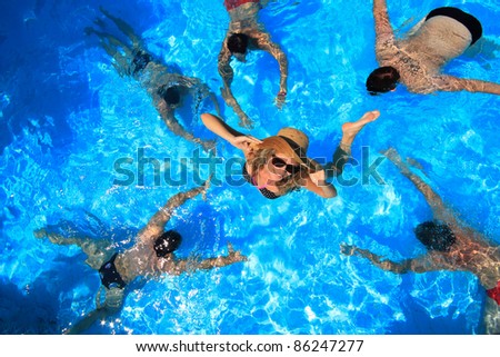 Young woman in a swimming pool surrounded by five man