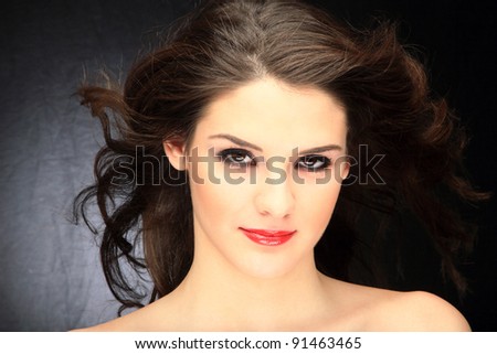 Glamour portrait of a woman on black with hair blowing with the wind