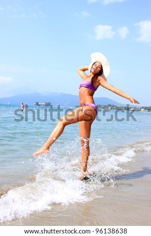 Bikini young girl is jumping up in the air at the beach