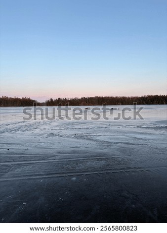 Similar – Image, Stock Photo Sunset over a frozen lake. Sunbeams falling on water. Shadows of trees on the ice covering the lake. Aerial view of a frozen lake. Ice sheet background. Frozen grass in water