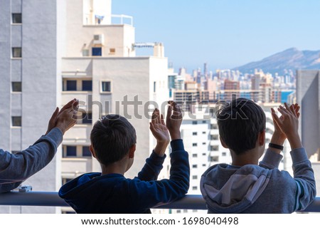 Family applauding medical staff from their balcony. People in Spain clapping gratitude on balconies and windows in support of health workers, doctors and nurses during the Coronavirus pandemic