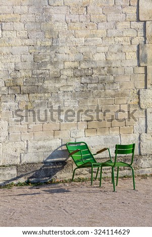 Stone wall and two green garden chairs in the morning sunlight in the Tuileries Garden, Paris, France (Vertical)