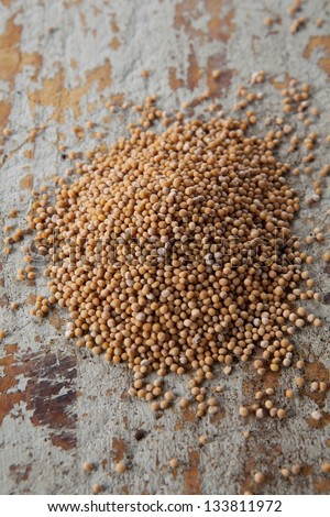 Yellow mustard seeds on a rustic background