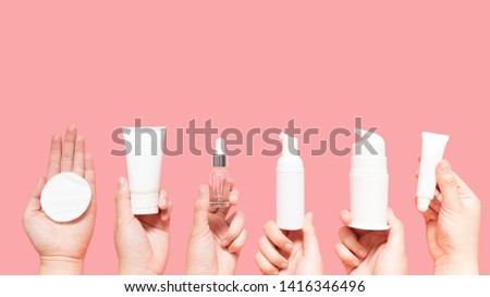 Skincare routine step for healthy skin - Woman hands holding facial cotton pad, foam, essential oil, serum, lotion and eye cream packaging on pink background. Beauty and cosmetic concept. Copy space. Stock foto © 