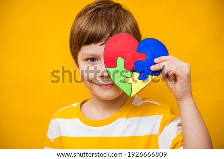 Kid boy hands holding puzzle heart, child mental health concept, world autism awareness day, teen autism spectrum disorder awareness concept