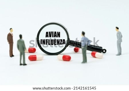 Medical concept. On a white surface are pills, figurines of people and a magnifying glass with the inscription - Avian Influenza Imagine de stoc © 