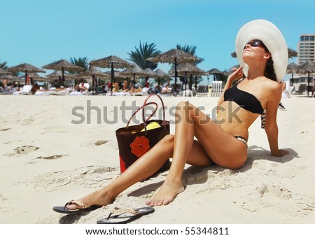 girl in a fashionable black bathing suit   and hat on the beach