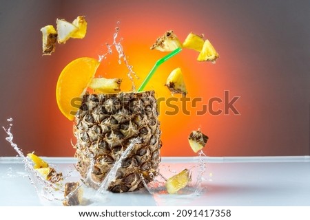 Pineapple cocktail. Pineapple with a straw. Flying pineapple slices and splashes. Citrus cocktail. Front view. Stok fotoğraf © 