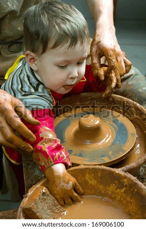 A potters hands guiding pupil hands to help him to work with the ceramic wheel