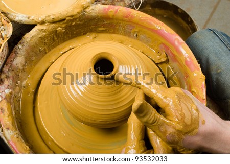 hands of a potter, creating an earthen jar of yellow clay