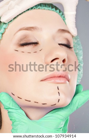 Plastic surgery hand touching the beautiful woman face.  Model is european beauty