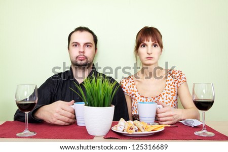 strange couple at the table drink tea and looking nowhere