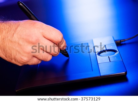 man's hand on drawing tablet in blue light