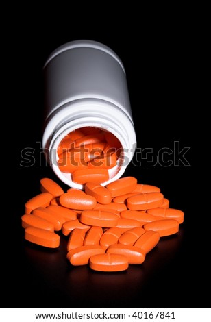 pills spilling from bottle isolated on black