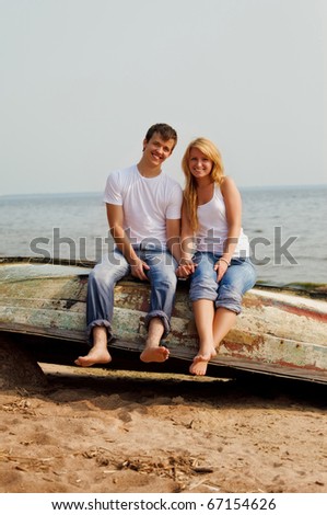 beautiful couple on a beach sitting on old boat