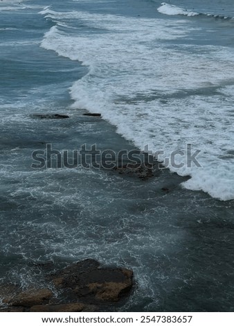 Foto Bild Blaue Wellen waschen felsiges Meeresufer mit Brücke bei hellem Wetter