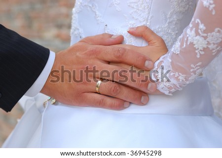 Hands of the groom and the bride with care about each other