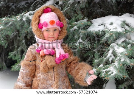 Girl in winter clothes at a snow-covered pine