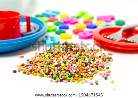 Plastic granules and children's toys made of plastic , polyethylene, polypropylene, pet polymer material on a white background. BPA FREE  toys Stock fotó © 