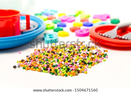 Plastic granules and children's toys made of plastic , polyethylene, polypropylene, pet polymer material on a white background. BPA FREE  toys Stock fotó © 