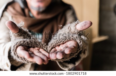 Closeup and focus dirty hands of poor man beggar. Old homeless man with gray beard wear gloves with sitting and hands up for help and food beggar because hungry. Help and hope concept. ストックフォト © 