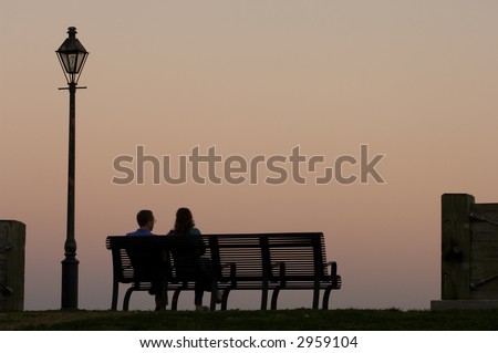 Couple sitting on the bench watching sunset by Mississippi river in New Orleans