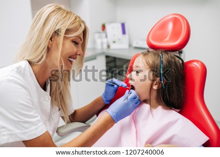 Cute little girl sitting on dental chair and having dental treatment. Foto d'archivio © 