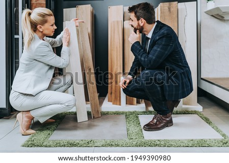 Middle age man choosing parquet and laminate flooring for his home and female seller helps him to make right decision. Photo stock © 