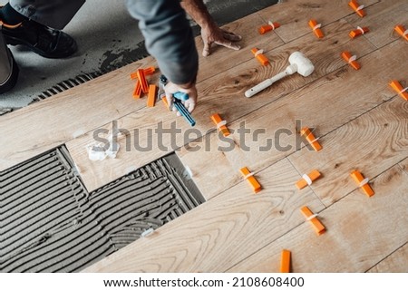 Professional tiler placing level in position with lash tile leveling system and clamp level ceramic tiles. Flooring and tiling concept. Foto stock © 