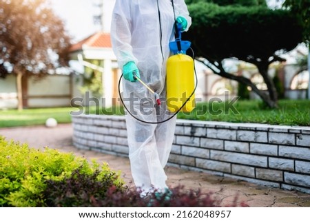 Exterminator in work wear outdoors spraying plants with a natural insecticide. ストックフォト © 