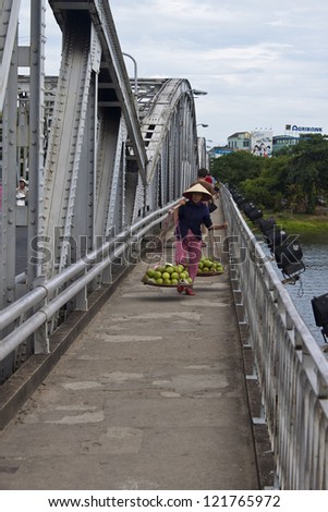 HUE, VIETNAM - JULY 31: Unidentified street vendor on a bridge over Perfume River  on July 31, 2012 in Hue, Vietnam. According to UNICEF, gross national income (GNI) for Vietnam in 2009 is USD$1,010.