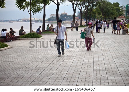 PNOM PENH, CAMBODIA - JULY 17: People walk at riverbank in Pnom Penh, Cambodia on July 17, 2012. Pnom Penh is the capital and largest city of Cambodia.. Metropolitan area is home to about 2.2 million.