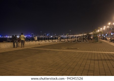 MUMBAI, INDIA - SEPTEMBER 5: Unidentified people walk on Marine Drive on September 5, 2011 in Mumbai, India. Marine Drive is a 3-kilometre-long boulevard in South Mumba. It is a road along the coast.