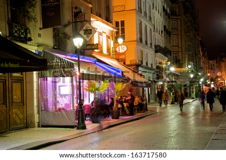 PARIS - SEPTEMBER 18: Romantic street cafe at night with several customers and pedestrians, many of them tourists in Paris, France, on September 18, 2013.