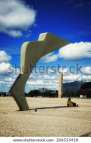 Rio de Janeiro, Brazil - June 17 2014: Man sitting under the shade of a sculpture in the city of Brasilia, in the Square of the Three Powers, on June 17, 2014.