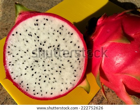 Dragon fruit cut in half, next to another dragon fruit