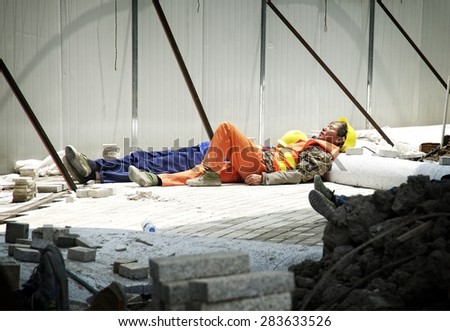 SHANGHAI, CHINA - MAY 2, 2015: Chinese construction worker resting under the sun, near the Hangpu River in Pudong. Shanghai is one of the fastest growing cities in the world.
